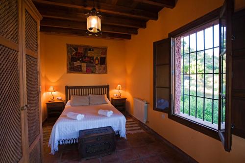 a bedroom with a bed and a large window at Villa La Torre Rocabella in El Chorro