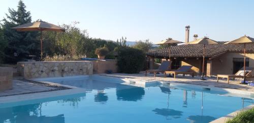 a pool with chairs and umbrellas next to a house at Cal Colina - Karaktervol landhuis met privé zwembad in Pacs del Penedes