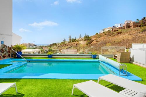 a swimming pool with green grass and a hill at Casa el Quijote in San Bartolomé de Tirajana