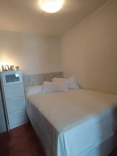 a small bedroom with a white bed and a dresser at Apartament - Monte Oiz - 2/4 pax + parking in Sierra Nevada