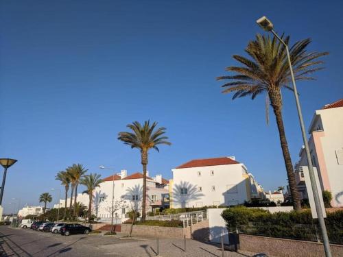 a street with palm trees and white buildings at Casa da Boa Gente in Cabanas de Tavira