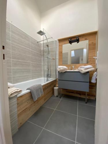 a bathroom with a tub and a sink and a mirror at Cocon en Champagne in Épernay