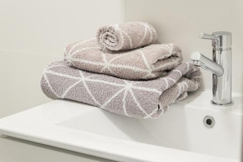 una pila de toallas sentadas en el lavabo del baño en T&K Apartments near Messe Fair Trade Düsseldorf und Airport 1B, en Duisburg