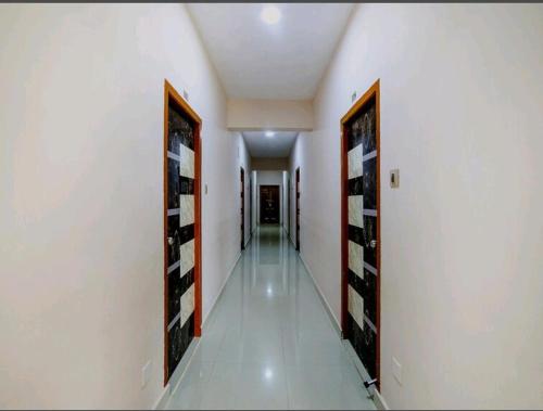 a hallway with two doors to a room with white walls at Nandas Grand in Nellore