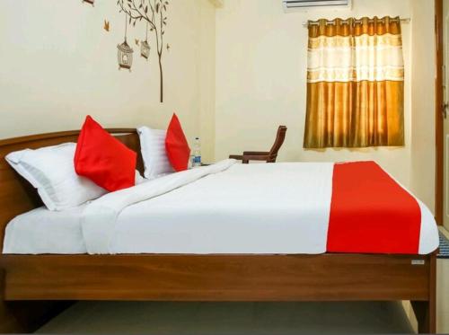 1 dormitorio con 1 cama blanca grande con almohadas rojas en Nandas Grand, en Nellore