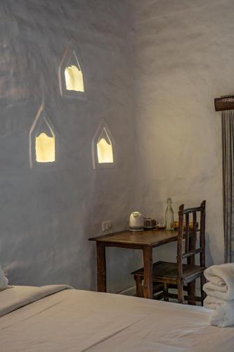 a bedroom with a table and a chair and a bed at Deshadan Eco Valley Resort - An Eco friendly Mud House in Kanthalloor