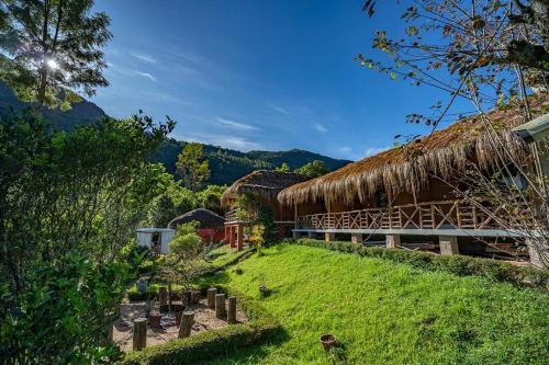 a building with a grass roof and a cemetery at Deshadan Eco Valley Resort - An Eco friendly Mud House in Kanthalloor
