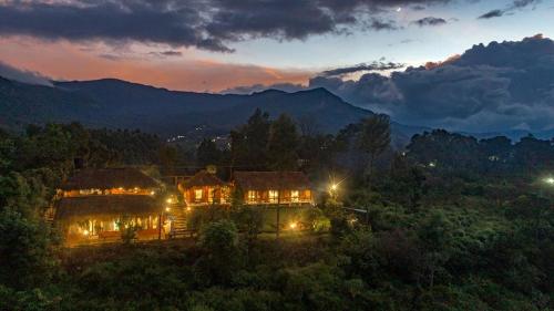 a house in the middle of a forest at night at Deshadan Eco Valley Resort - An Eco friendly Mud House in Kanthalloor