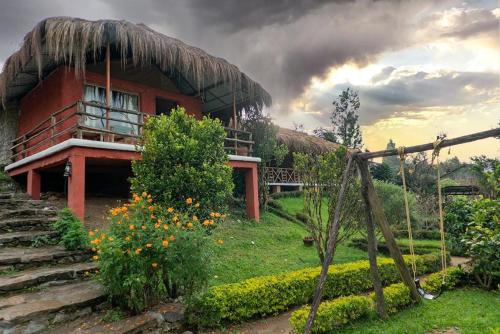 a house with a thatch roof on a hill at Deshadan Eco Valley Resort - An Eco friendly Mud House in Kanthalloor