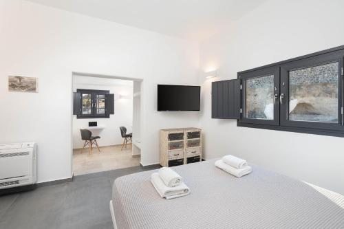- une chambre blanche avec un lit et une télévision dans l'établissement Alios villa, à Imerovigli