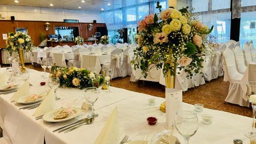 a room with white tables with white chairs and flowers at Hotel Magistern Konferencia és WellnessHotel in Siófok