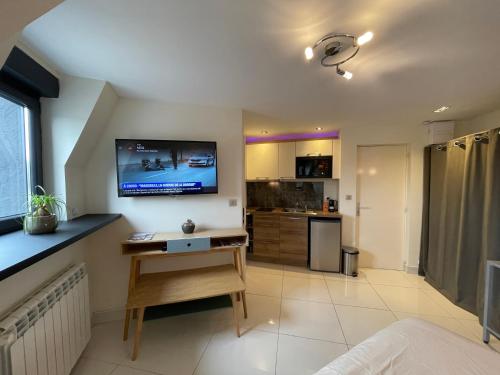 Elle comprend un salon avec un bureau et une télévision murale. dans l'établissement RDC 4 - Studio meublé centre ville de Montluçon, à Montluçon