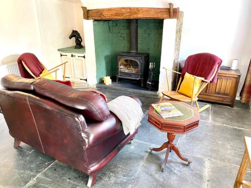 a living room with a leather couch and a fireplace at Badges Cottage for 5 Near Dartmoor Beaches and Pub in Holsworthy