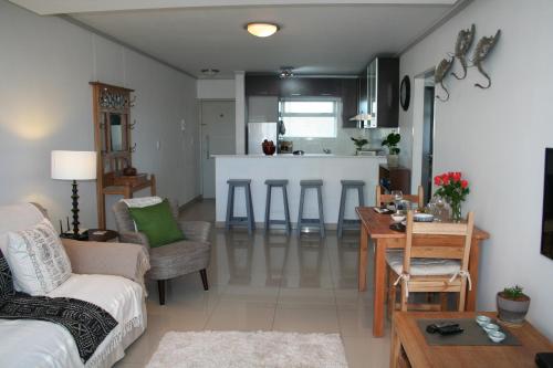 sala de estar con sofá, mesa y cocina en The Quadrant, G505, en Ciudad del Cabo