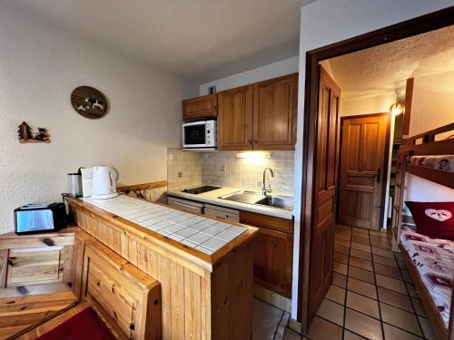 Elle comprend une petite cuisine avec des placards en bois et un évier. dans l'établissement Elior 2 - 2 pieces proche pistes, à La Clusaz