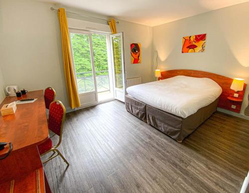 a bedroom with a bed and a desk and a window at Logis H&ocirc;tel - Restaurant Le Tulipier in Vienne-le-Ch&acirc;teau