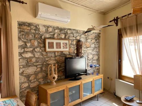 - un salon avec une télévision sur un mur en pierre dans l'établissement Sofia's Apartment, à Skiathos Chora