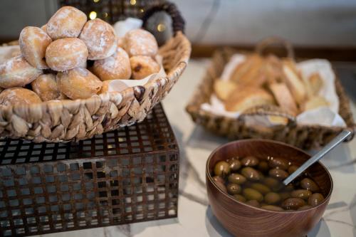 a table with baskets of doughnuts and a bowl of olives at Kappa Resort in Paliouri