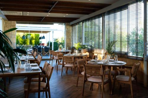 a restaurant with tables and chairs and large windows at Kappa Resort in Paliouri