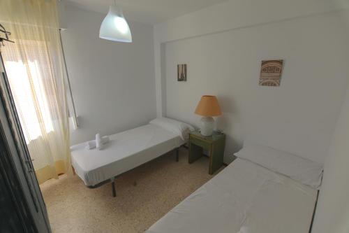 a white room with two beds and a lamp at RentalSevilla Luminoso apartamento 3 dormitorios in Seville