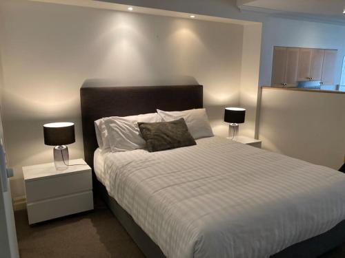 a bedroom with a large bed with two lamps at CBD Corporate Apartment BON002810 in Sydney