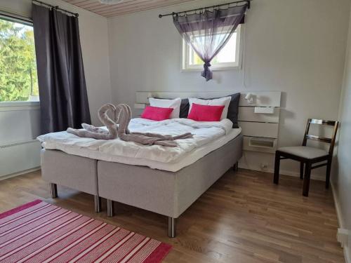 een slaapkamer met een groot bed met rode kussens en een stoel bij Villa Silve, yhden makuuhuoneen omakotitalo. in Lohja