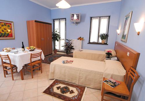 a room with two beds and a table and chairs at Casa Vacanze Provenzale in Torre Pellice