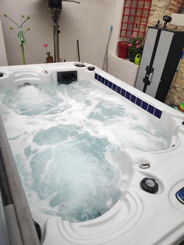 a white bath tub filled with water in a bathroom at Entre Bourges et Sancerre, vacances relaxantes in Les Aix-dʼAngillon