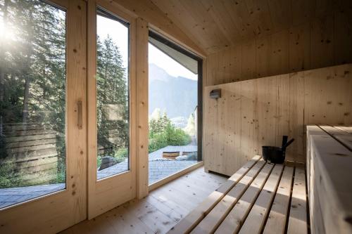 a wooden room with large windows and a bench at Stelza Nature Chalet in Val di Vizze