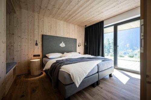a bedroom with a large bed and a large window at Stelza Nature Chalet in Val di Vizze