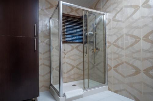 y baño con ducha y puerta de cristal. en Alvanti Residences en Accra