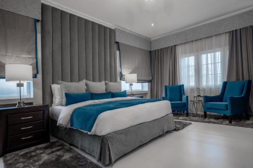 アクラにあるAlvanti Residencesのベッドルーム1室(大型ベッド1台、青い椅子2脚付)