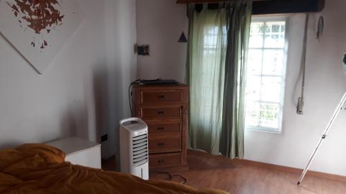 a bedroom with a bed and a dresser and a window at casa de campo a 40 km de Rosario in Villa Amelia