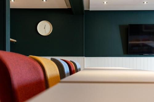 a room with a clock on a green wall and chairs at Westmorland Hotel Tebay in Tebay