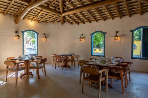 a dining room with tables and chairs and windows at DA GRAÇA HOTEL in Trancoso