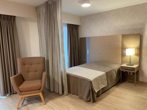 ein Schlafzimmer mit einem Bett, einem Stuhl und einer Lampe in der Unterkunft Aix-les-Bains Appart'S in Aix-les-Bains
