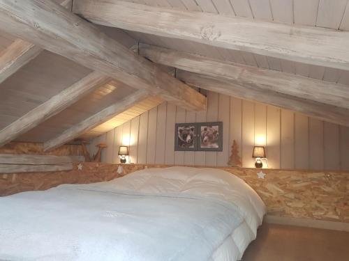 a bedroom with a large white bed with wooden ceilings at Chalet avec SPA, sauna, billard, proche Paradiski in Aime-La Plagne