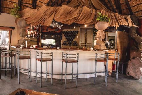 a bar with stools at a counter in a room at Bass Lake Country Lodge in Pretoria