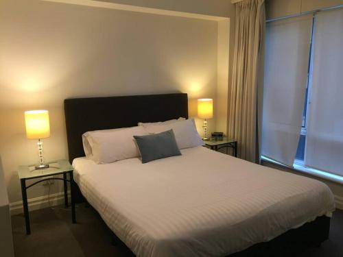 a bedroom with a large white bed with two lamps at Heart of SYDNEY CBD - studio apartment B412 in Sydney