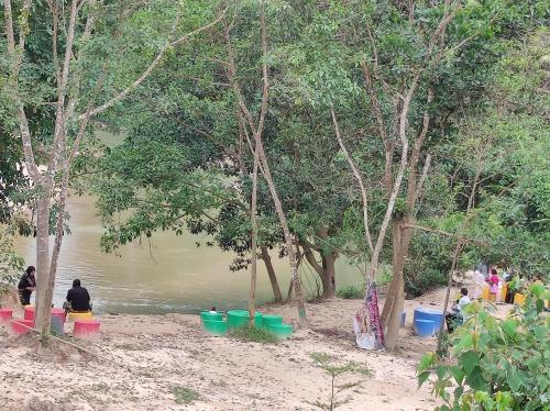 a group of people sitting on a beach near a body of water at CTZ PAROH RIVER PARK in Jertih