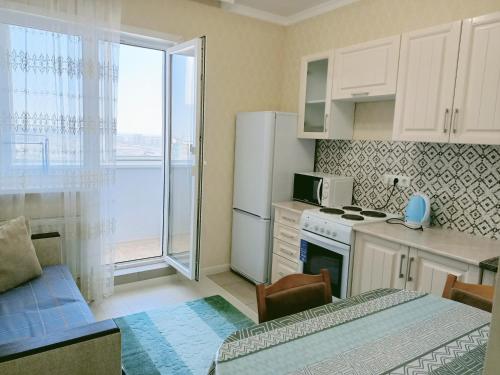 a kitchen with a refrigerator and a table and a microwave at Однокомнатная квартира в ЖК Millennium Park in Astana