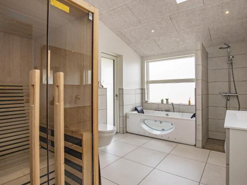 La salle de bains est pourvue d'une baignoire, d'un lavabo et de toilettes. dans l'établissement Holiday home Oksbøl LXXXIV, à Oksbøl