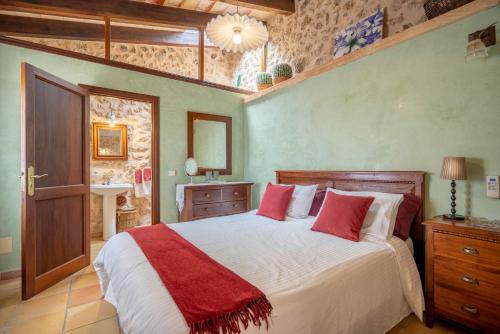 CAN PULIT - finca romántica para 2 con piscina y vistas en Selva Mallorca في سيلفا: غرفة نوم بسرير كبير ومخدات حمراء