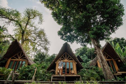 a man standing in front of a house with trees at The Tropical Koh Mook in Koh Mook