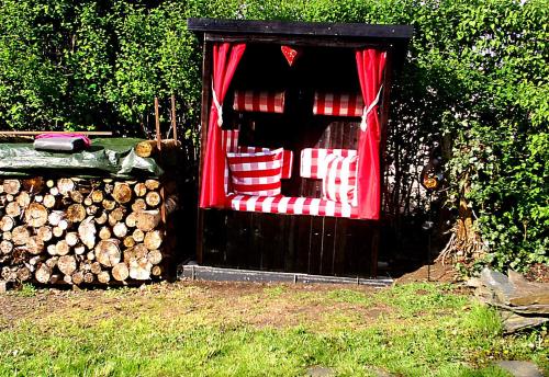 a wooden cabin with red curtains and a pile of logs at Ferienwohnung Lachmann in Benneckenstein