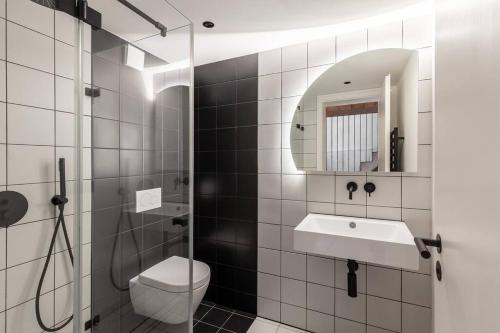 y baño con aseo, lavabo y espejo. en Black White 44sqm 2room maisonette apt near center en Berlín