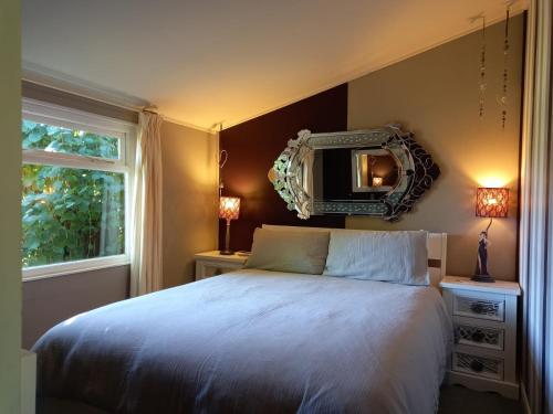 a bedroom with a bed and a mirror on the wall at Adorable Hideaway with log fire and incredible views in Robertsbridge