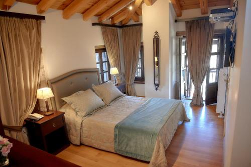 a bedroom with a bed and two lamps and windows at Archontiko Deligianni in Dhimitsana