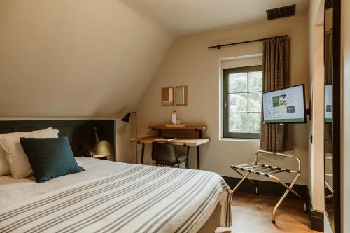 a bedroom with a bed and a window and a desk at Auberge du Pêcheur in Sint-Martens-Latem