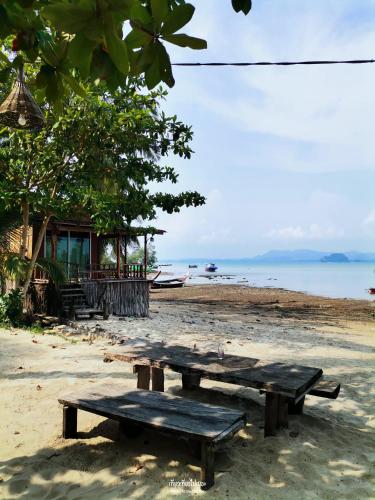 a picnic table on a beach next to the water at The Tropical Koh Mook in Koh Mook